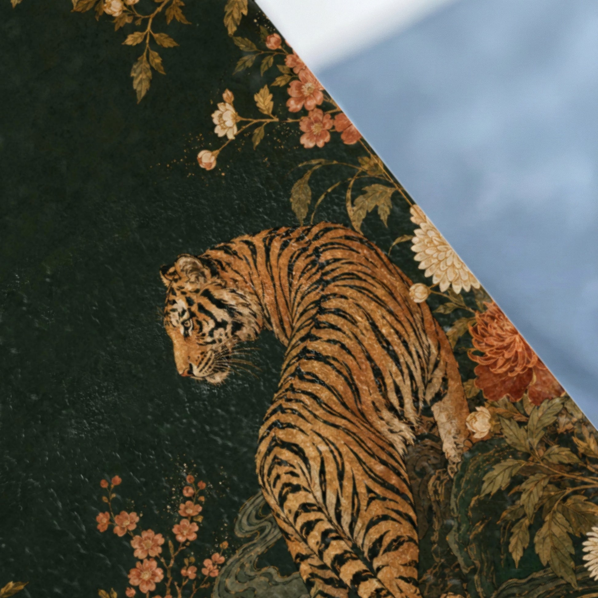 Tiger amongst dark green floral patterns and foliage, right side blurred.