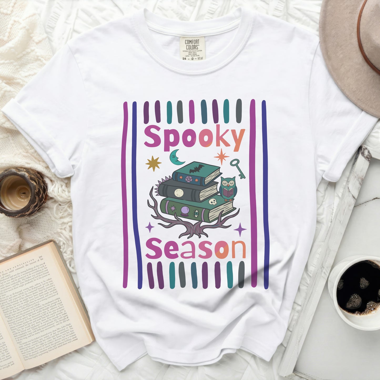 White t-shirt with "Spooky Season" graphic featuring books, owl, and Halloween icons.