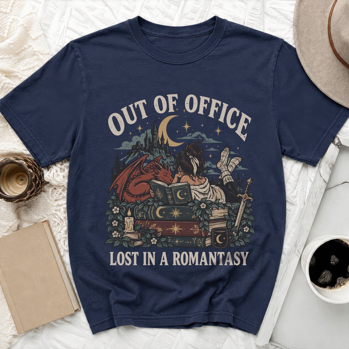 Dark blue t-shirt graphic with dragon, books, and text "OUT OF OFFICE LOST IN A ROMANTASY".
