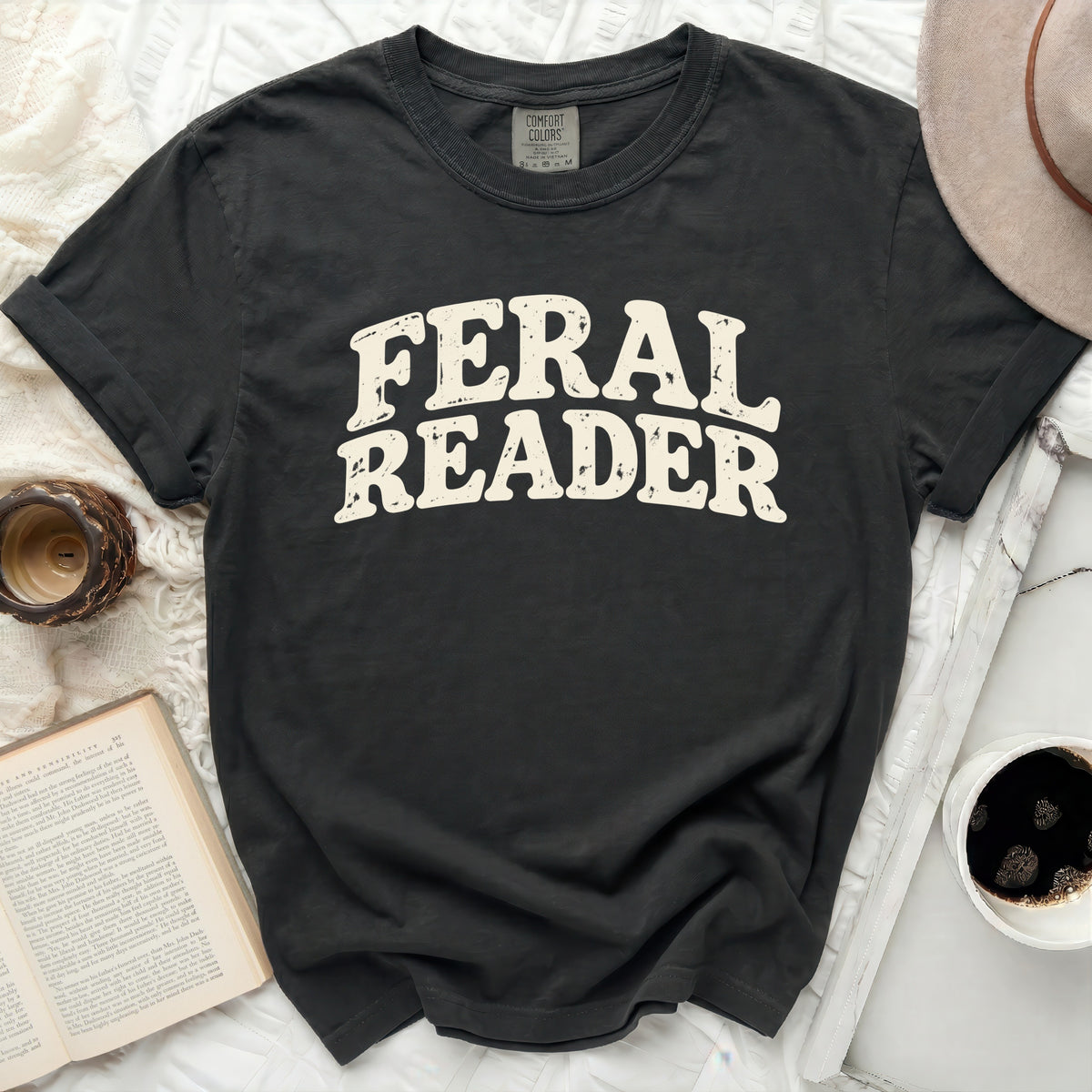 Dark gray t-shirt with "FERAL READER" text in distressed cream font.