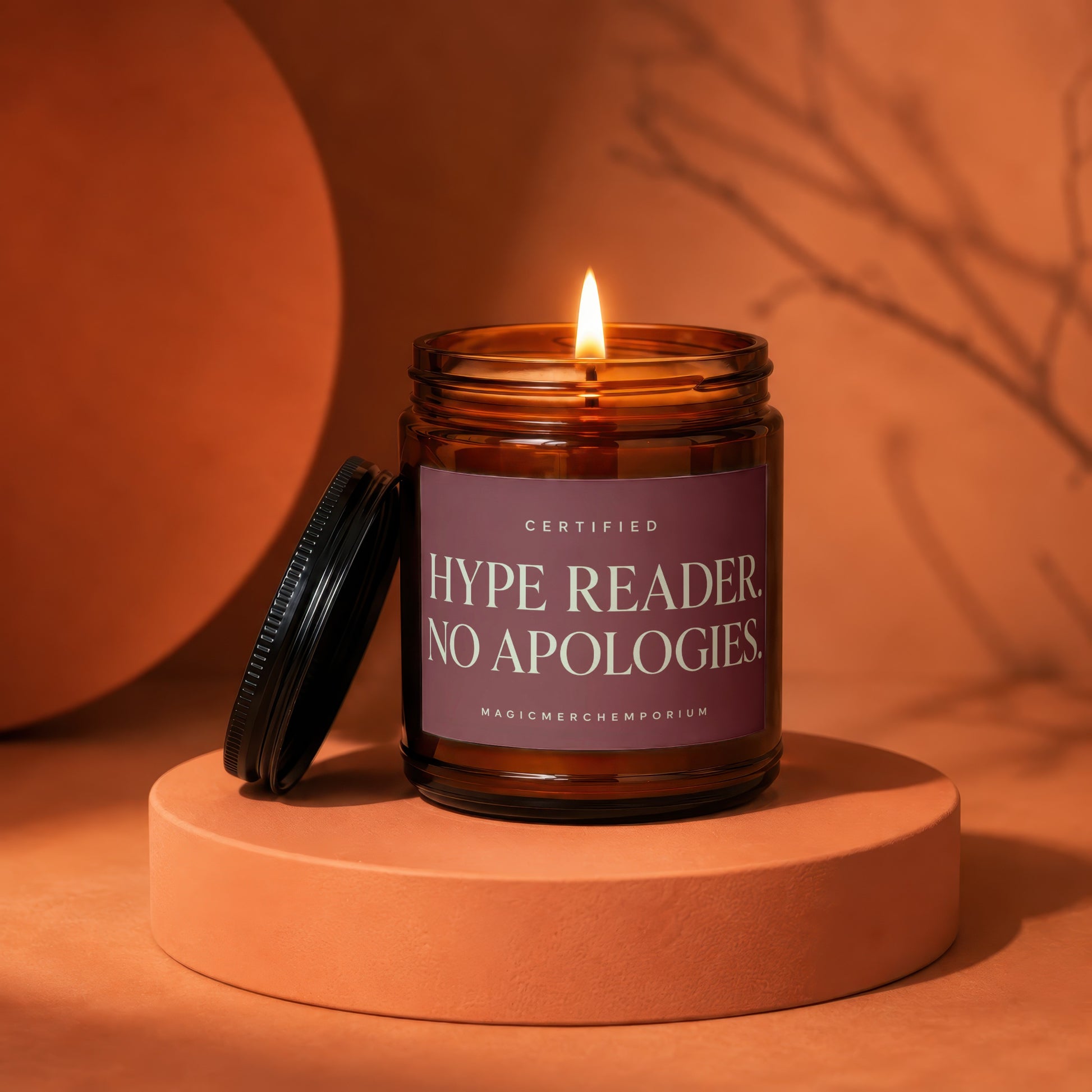 Amber jar candle, lit, with "CERTIFIED HYPE READER. NO APOLOGIES." label.
