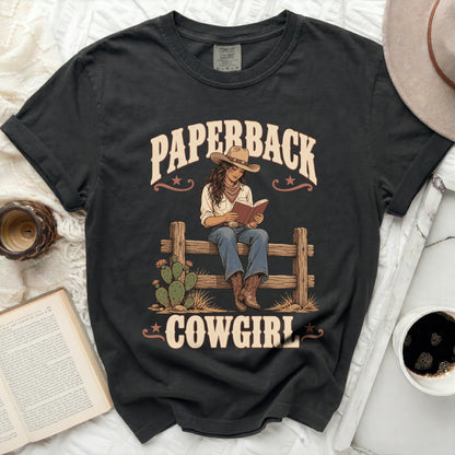 Black t-shirt graphic with "Paperback Cowgirl" text and illustration of a cowgirl reading.