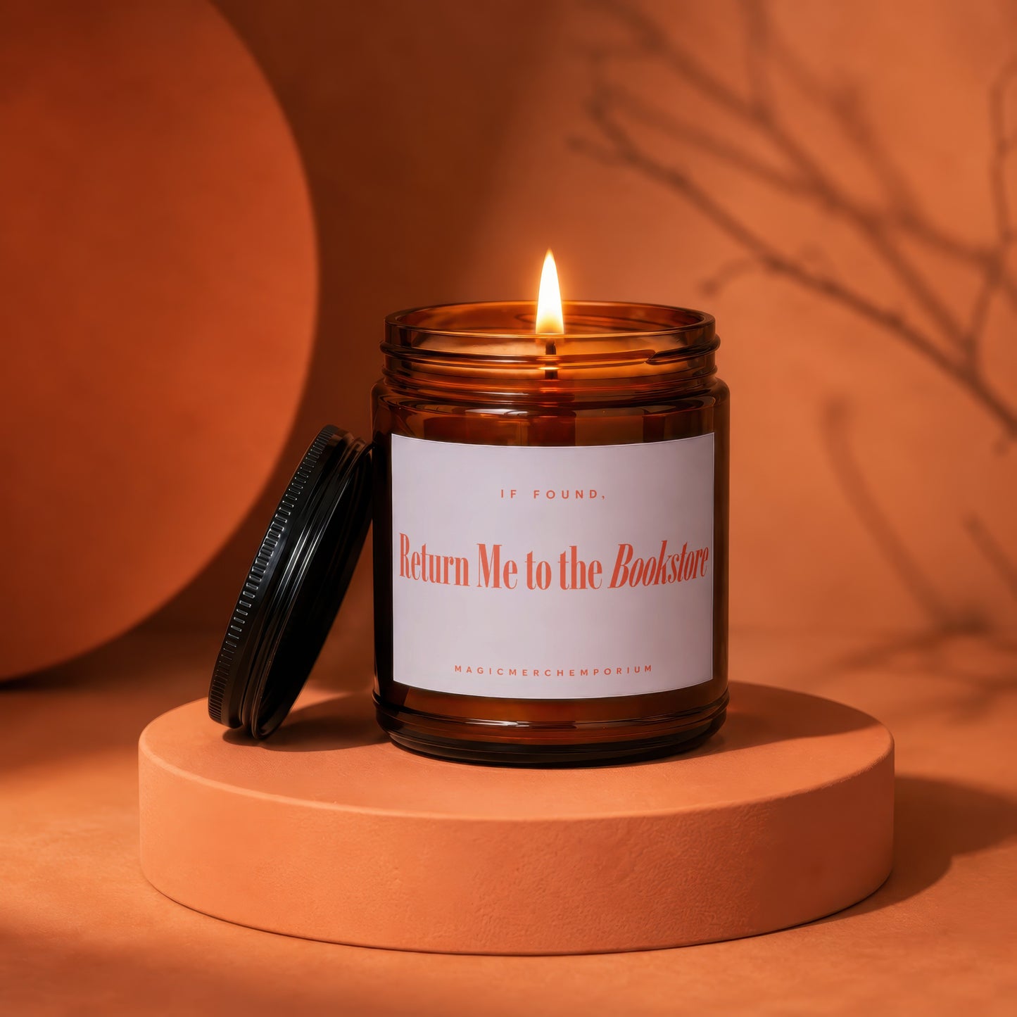 Lit amber jar candle with "Return Me to the Bookstore" text on a pedestal.