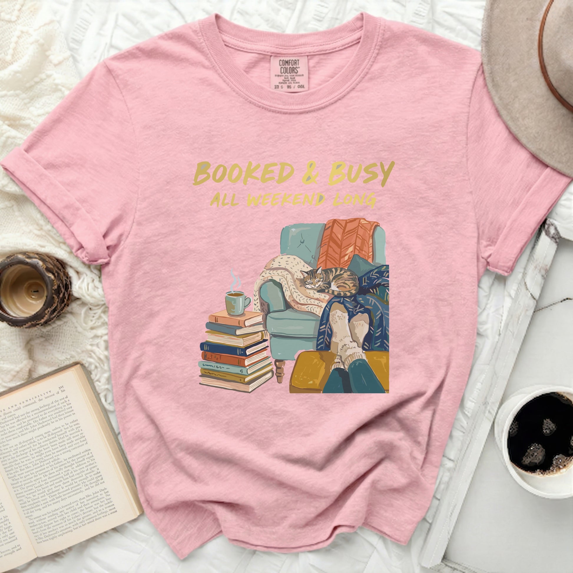 Pink t-shirt with "Booked & Busy" text and cat on books.