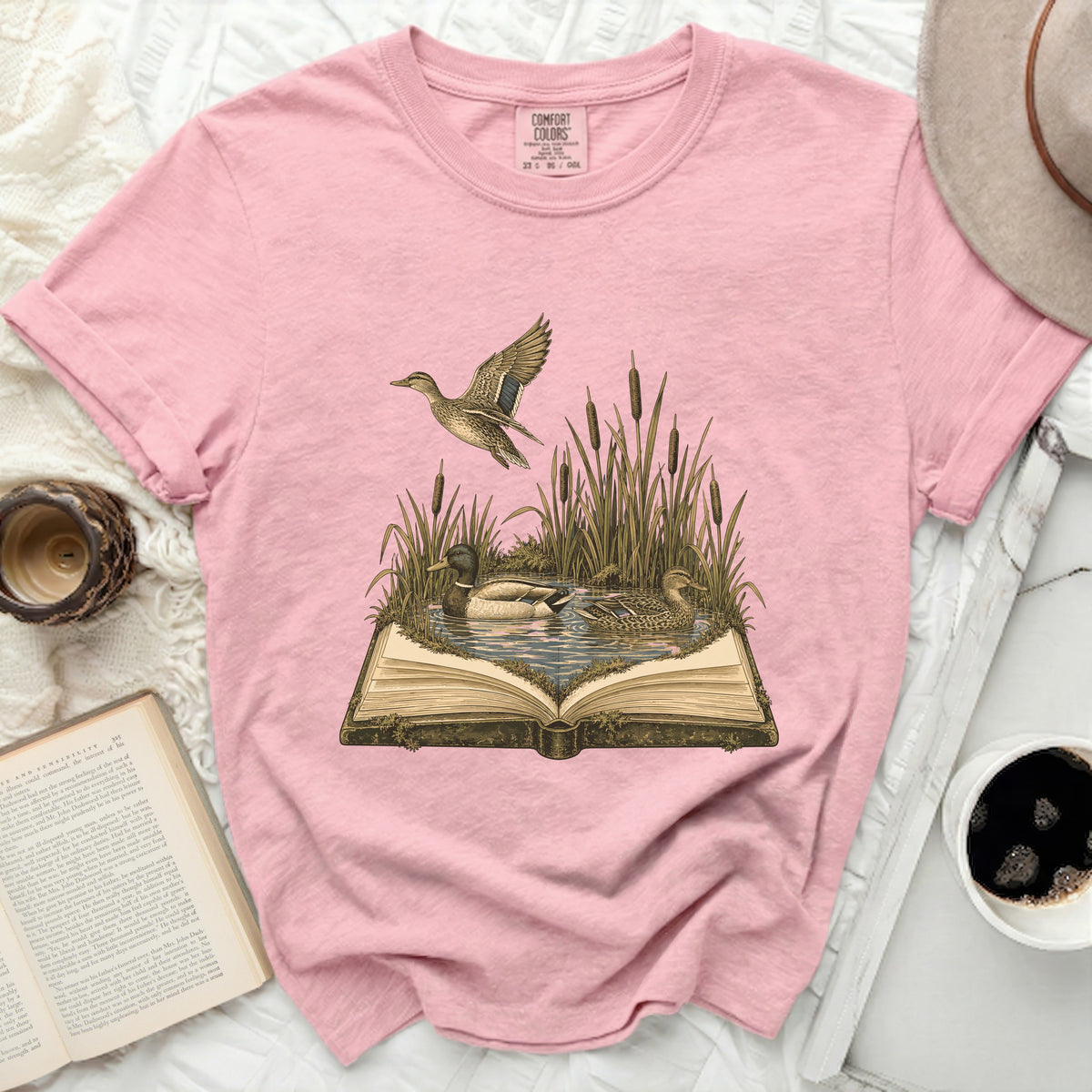 Pink t-shirt with a vintage illustration of ducks in a pond emerging from an open book.