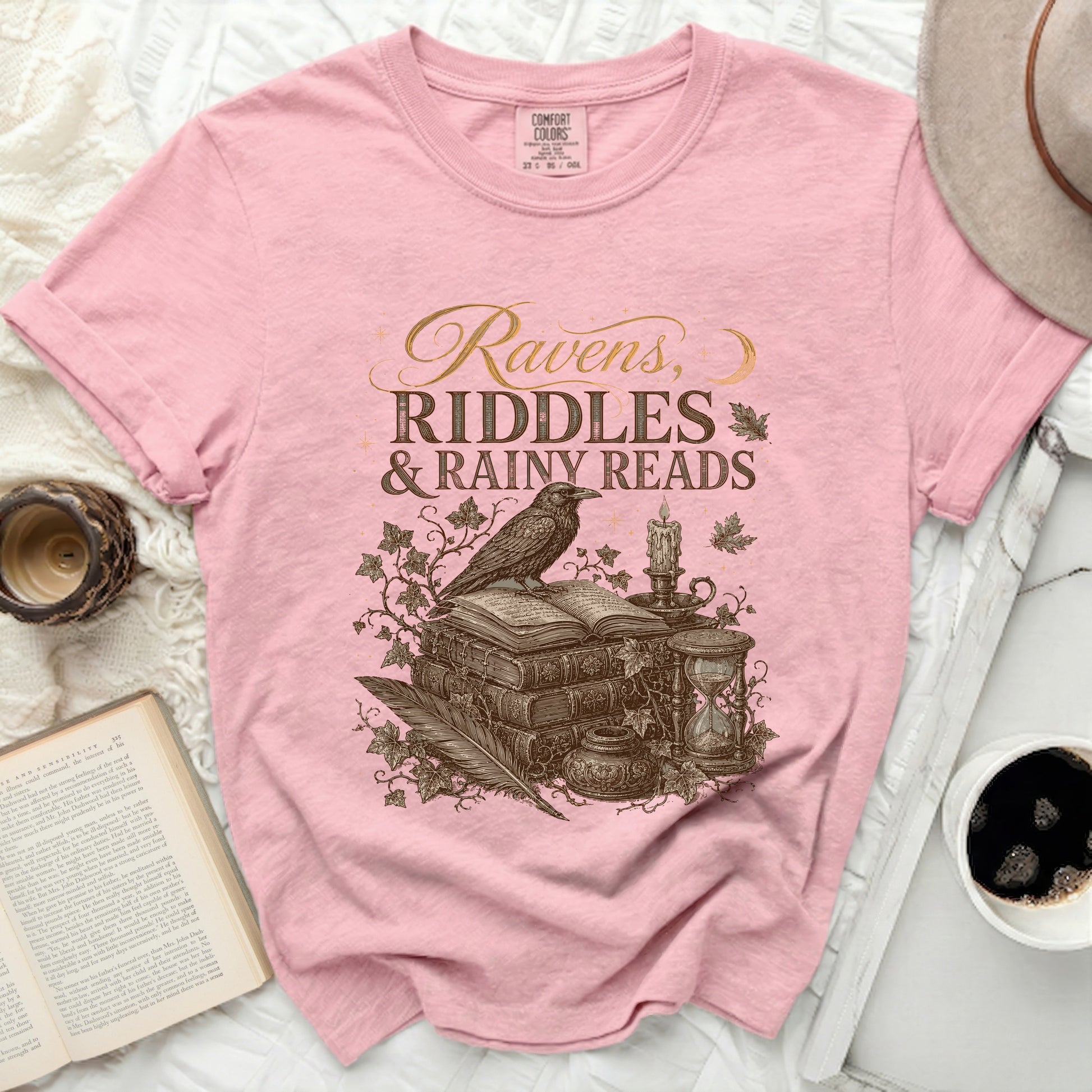 Pink t-shirt with "Ravens, Riddles & Rainy Reads" graphic and vintage book detail.