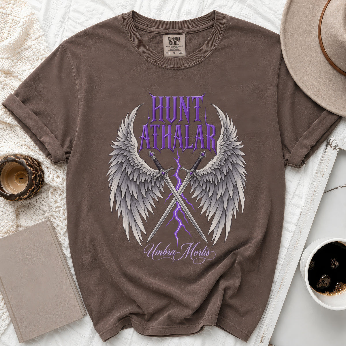 Brown t-shirt with "Hunt Athalar" and "Umbra Mortis" text, wings, and swords graphic.