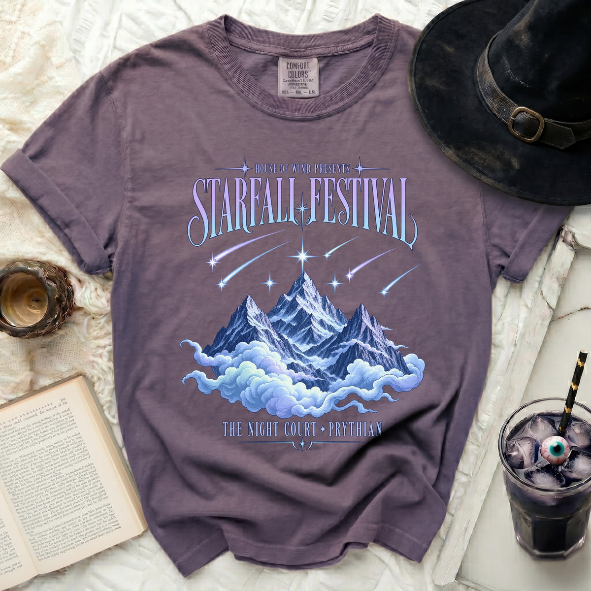 Purple t-shirt with "Starfall Festival" and mountains with clouds graphic.