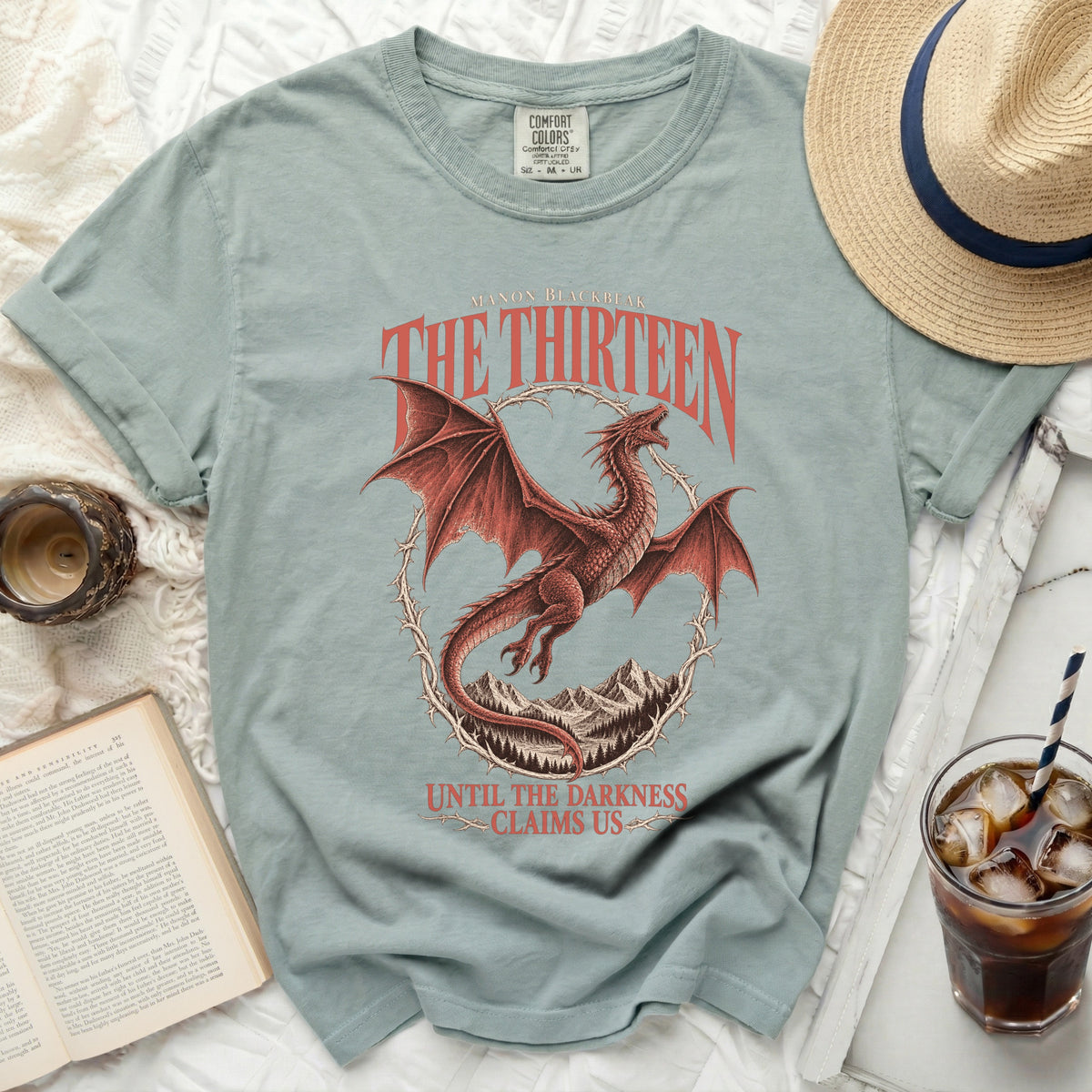 Light teal t-shirt with red dragon, mountains, and text "The Thirteen".