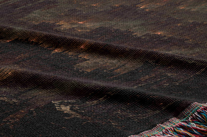 a close-up view of a dark, textured fabric with a pattern resembling a city skyline. The fabric appears to be made of a woven material, with a dark brown or black color. The image does not contain any text or other discernible objects or actions.