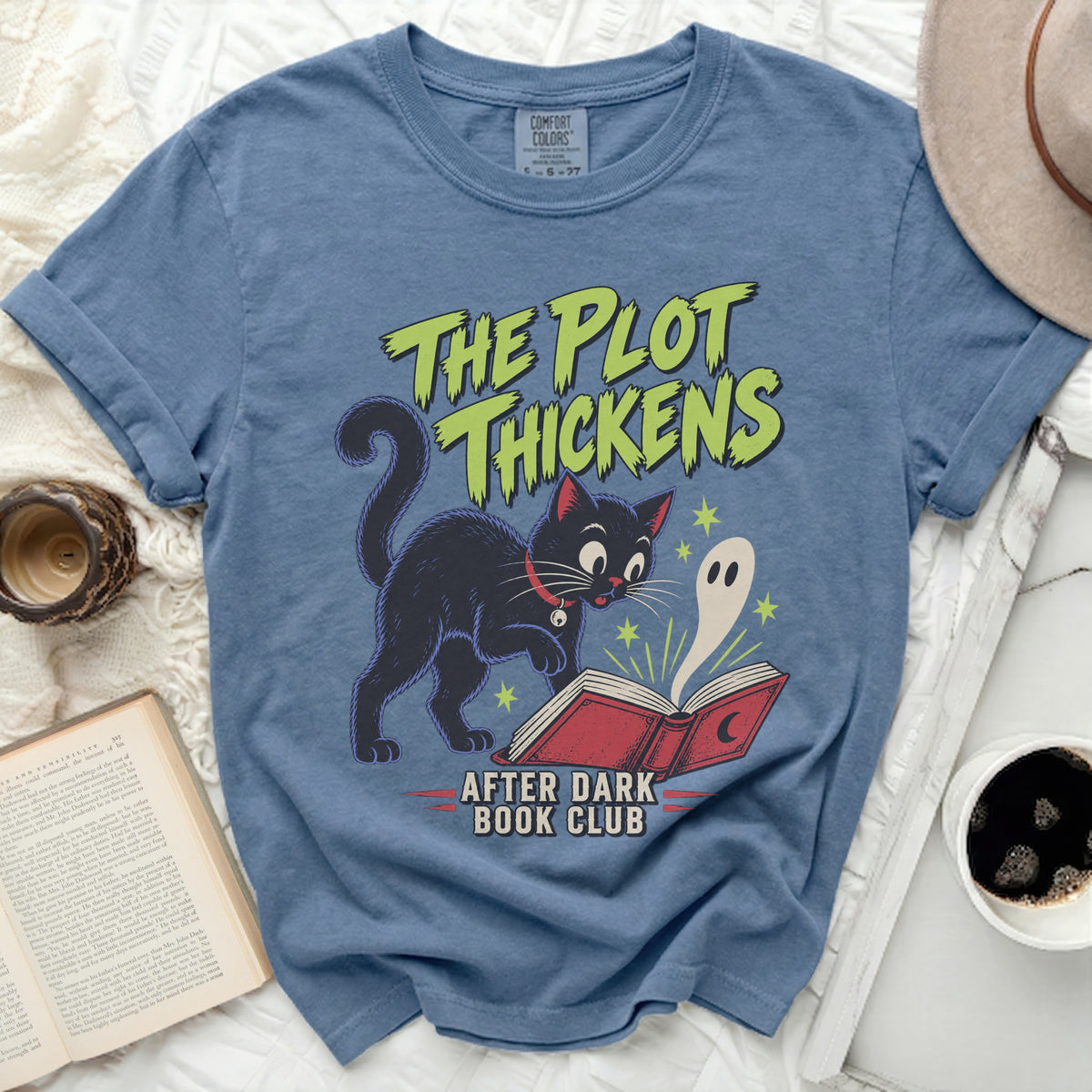 Blue t-shirt with a black cat and ghost reading a book, reading "The Plot Thickens".