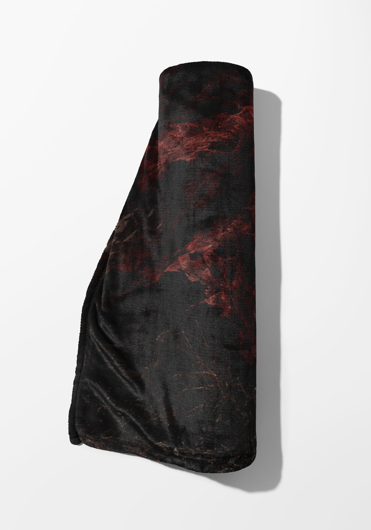 Rolled black blanket with abstract red and brown marbling pattern.