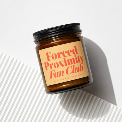 Amber jar candle with "Forced Proximity Fan Club" text on a tan label.