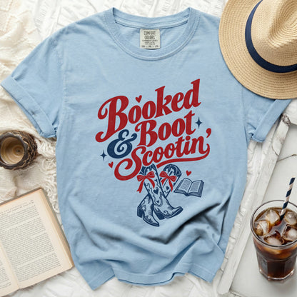 Light blue t-shirt with "Booked & Boot Scootin'" text, cowboy boots, and an open book.