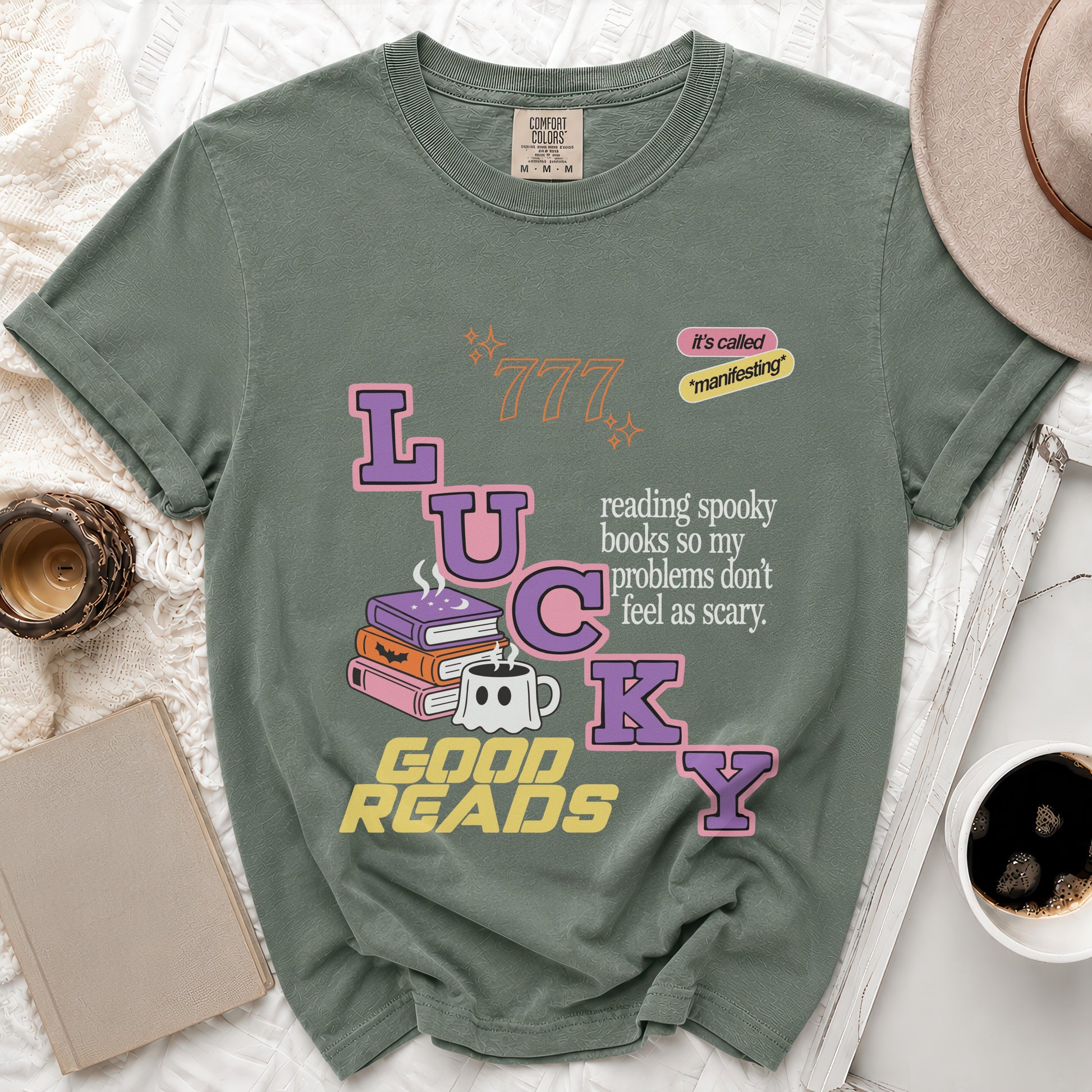 Sage green t-shirt with "Lucky" text, spooky, books, ghost mug, and "Good Reads."