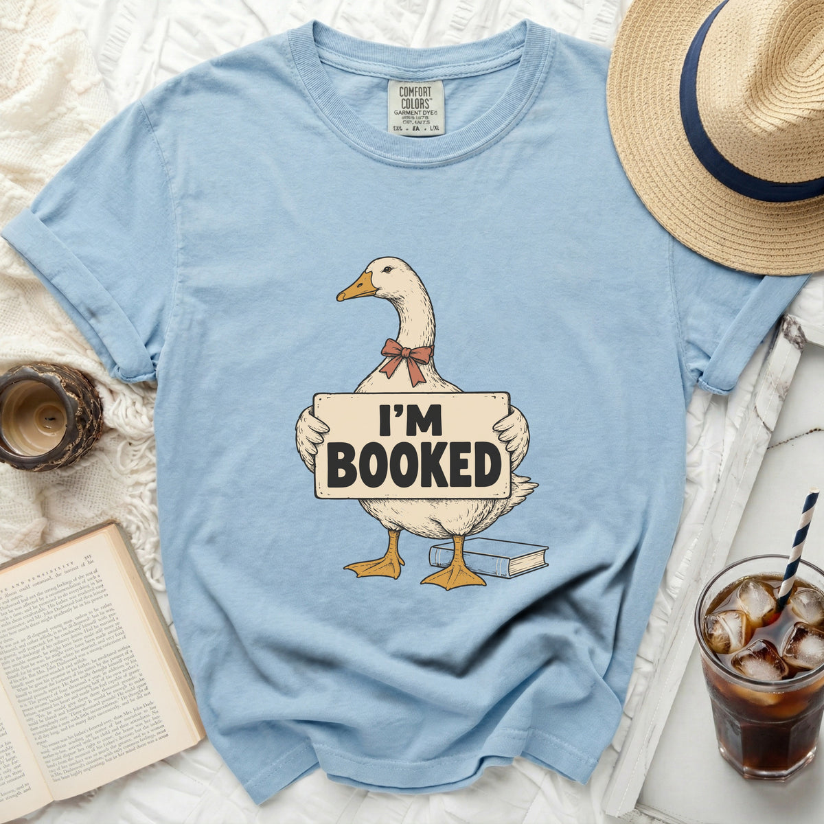 Light blue t-shirt with a goose graphic holding "I'M BOOKED" sign.
