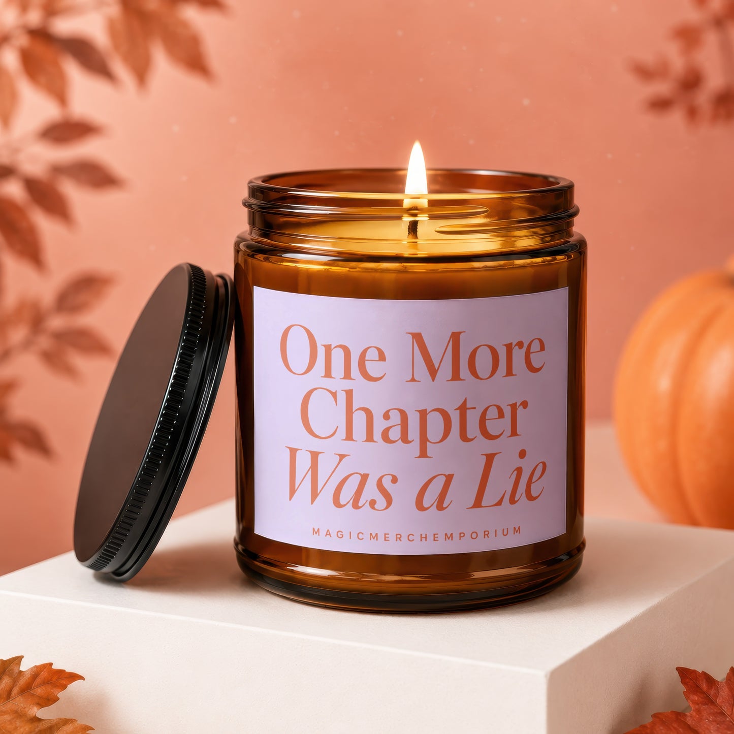 Lit amber glass candle with "One More Chapter Was a Lie" text.