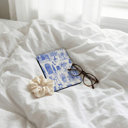 Blue toile print coaster with scrunchie and glasses on rumpled white sheets.
