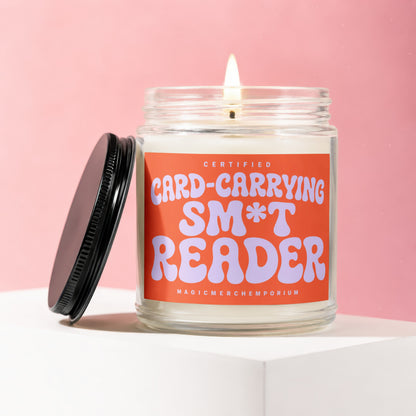 Candle with orange label reading "CERTIFIED CARD-CARRYING SM*T READER".