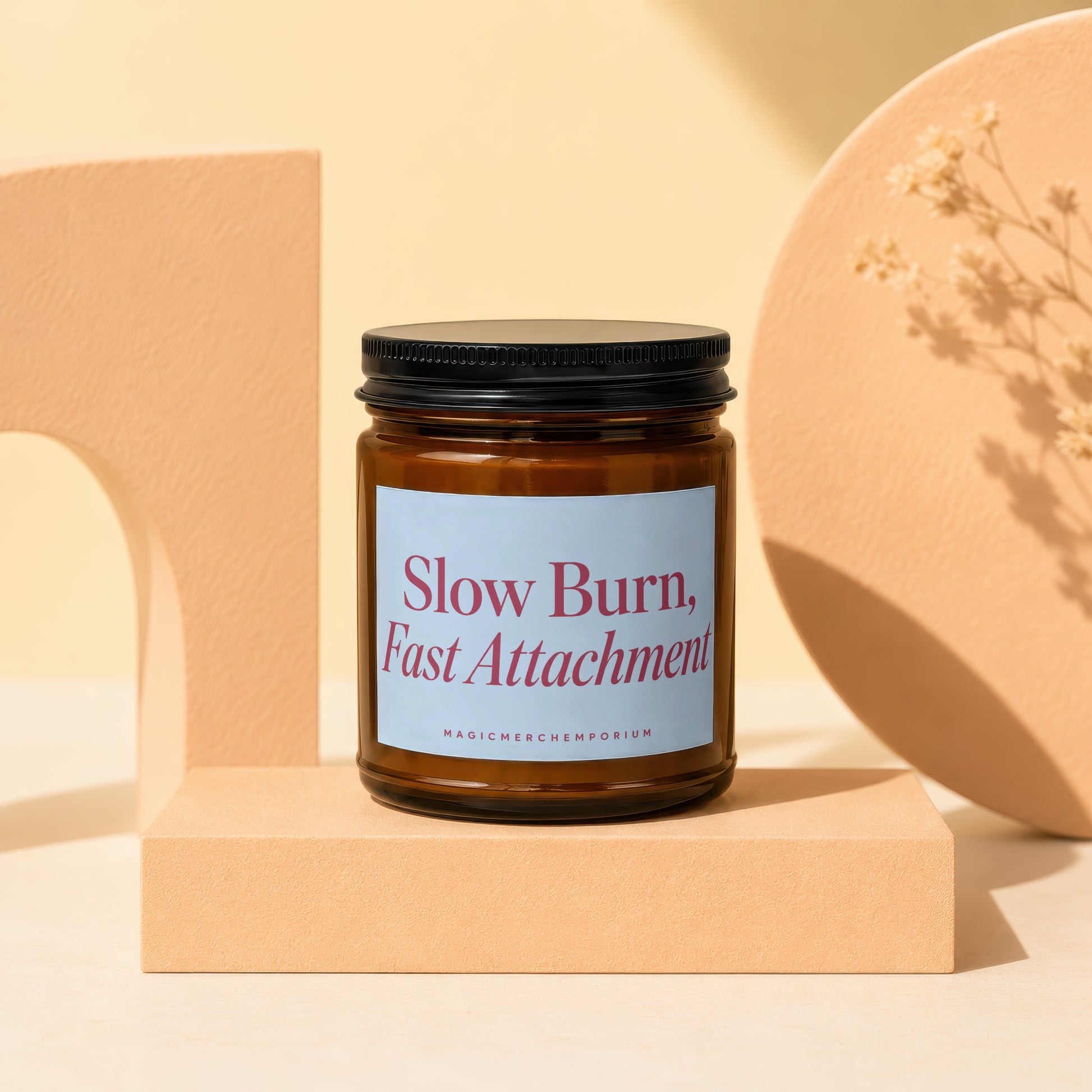 Amber glass candle with black lid, label reads "Slow Burn, Fast Attachment."