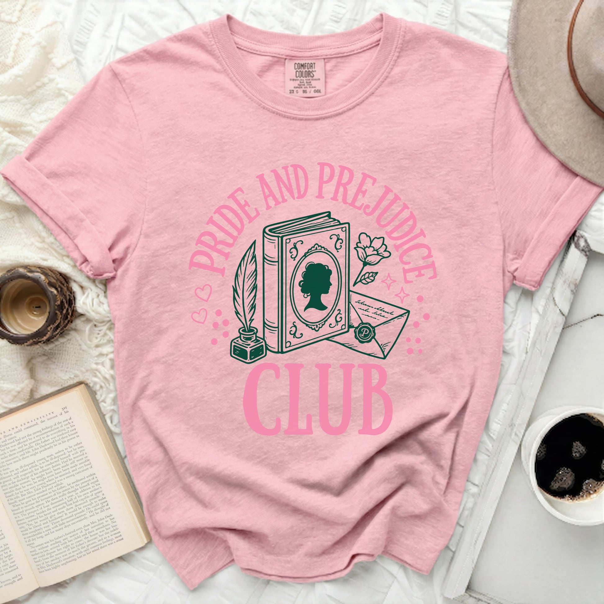 Pink t-shirt with "Pride And Prejudice Club" graphic featuring a book, quill, and letter.