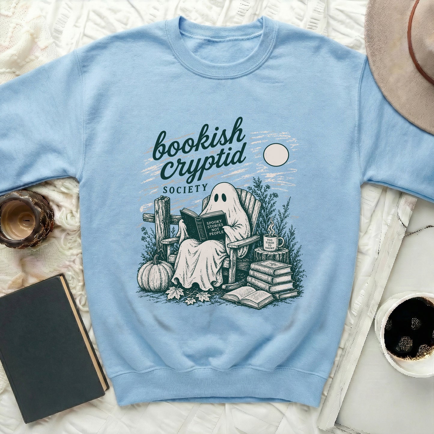Light blue sweatshirt with "bookish cryptid SOCIETY" and ghost reading "Spooky Stories Not People."