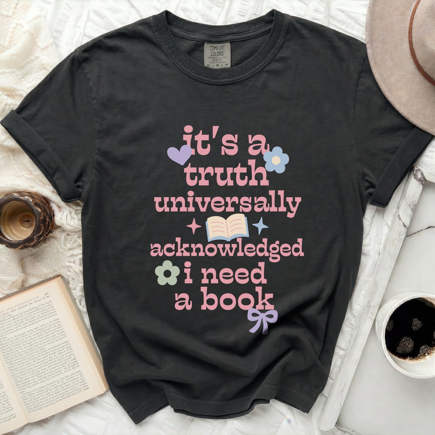 Black t-shirt with pink text "it's a truth universally acknowledged i need a book".