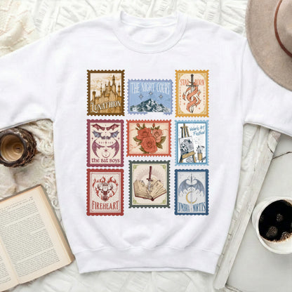 White sweatshirt with nine postage stamp designs of fantasy scenes and text.