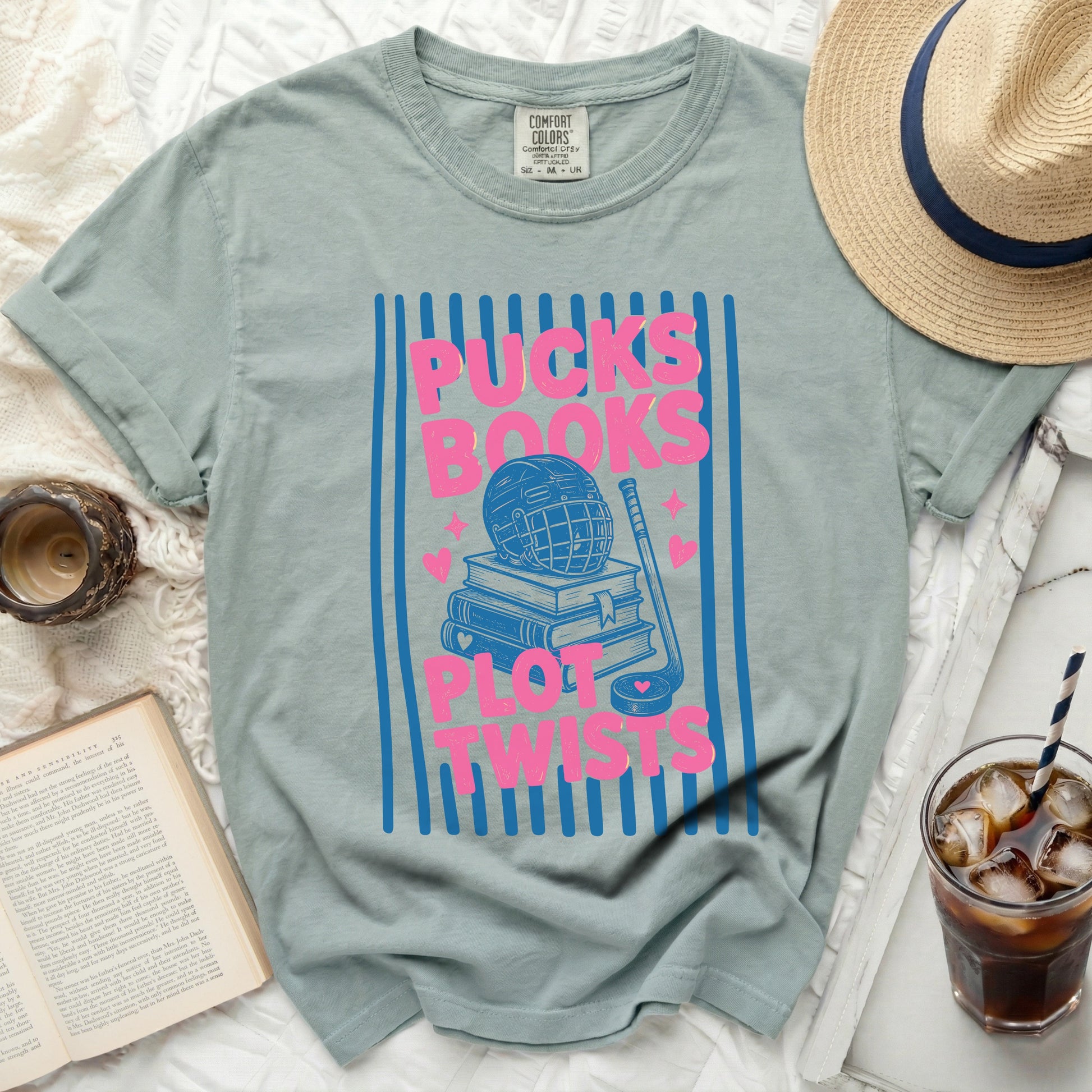 T-shirt with "Pucks, Books, Plot Twists" and hockey graphic on blue stripes.