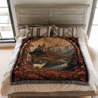 a bed with a large, colorful tapestry or blanket on it. The tapestry depicts a scenic landscape with mountains, a castle, and a deer. The bed is set against a white wall, and there are pillows on the bed.