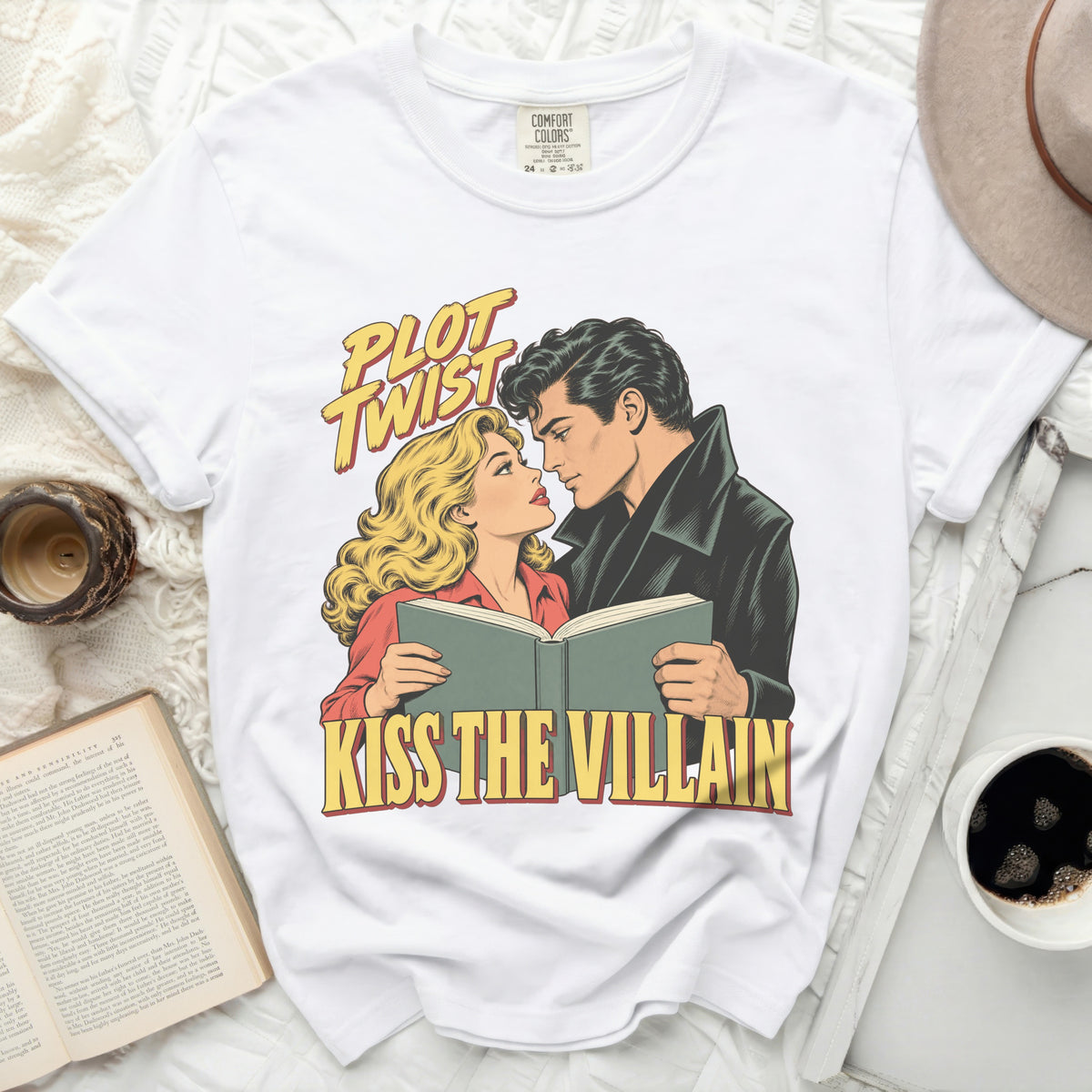 White t-shirt with comic art of couple reading a book and text "Plot Twist Kiss the Villain."