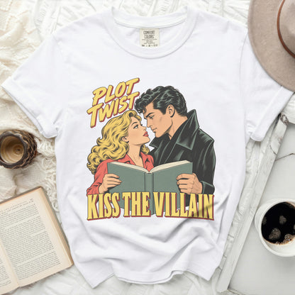 White t-shirt with comic art of couple reading a book and text "Plot Twist Kiss the Villain."