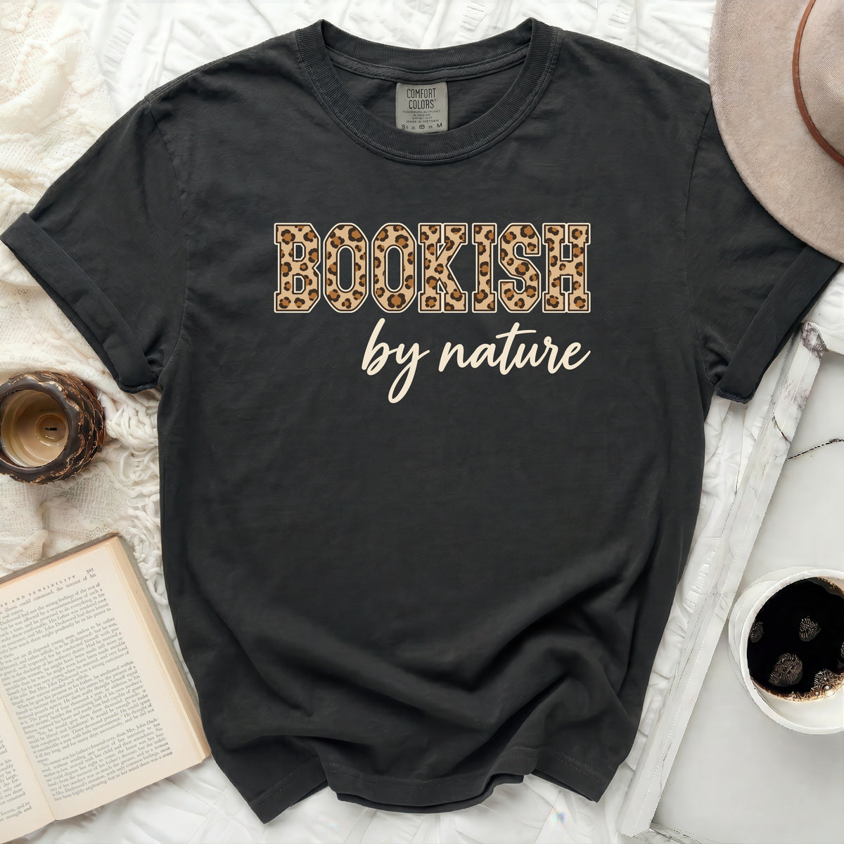 Black t-shirt with "BOOKISH by nature" text in leopard print and script font.