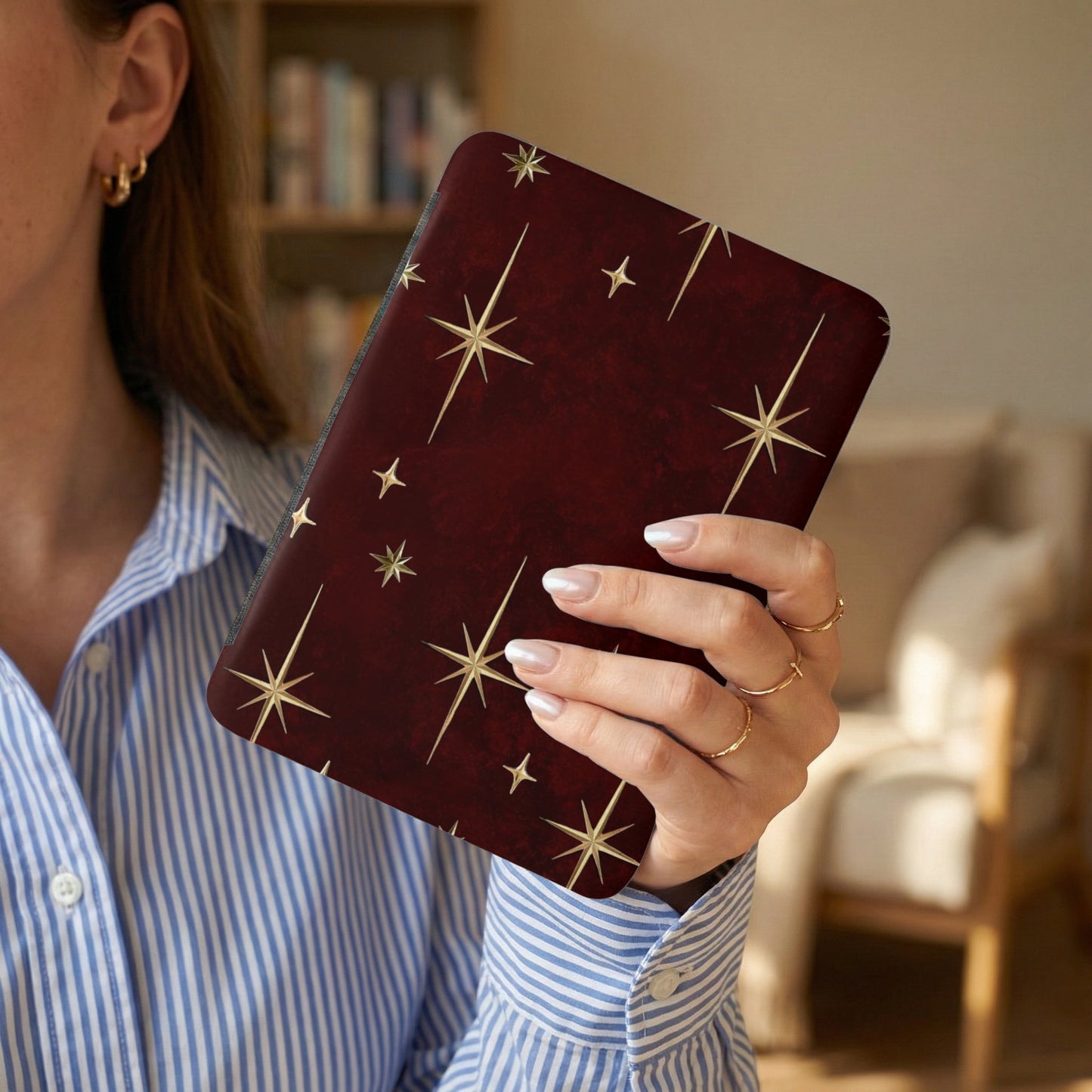 Dark red case with scattered gold starbursts held by a woman.