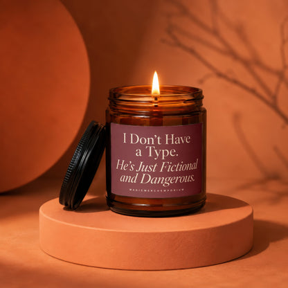 Amber candle with lit flame and label reading "I Don't Have a Type. He's Just Fictional and Dangerous."
