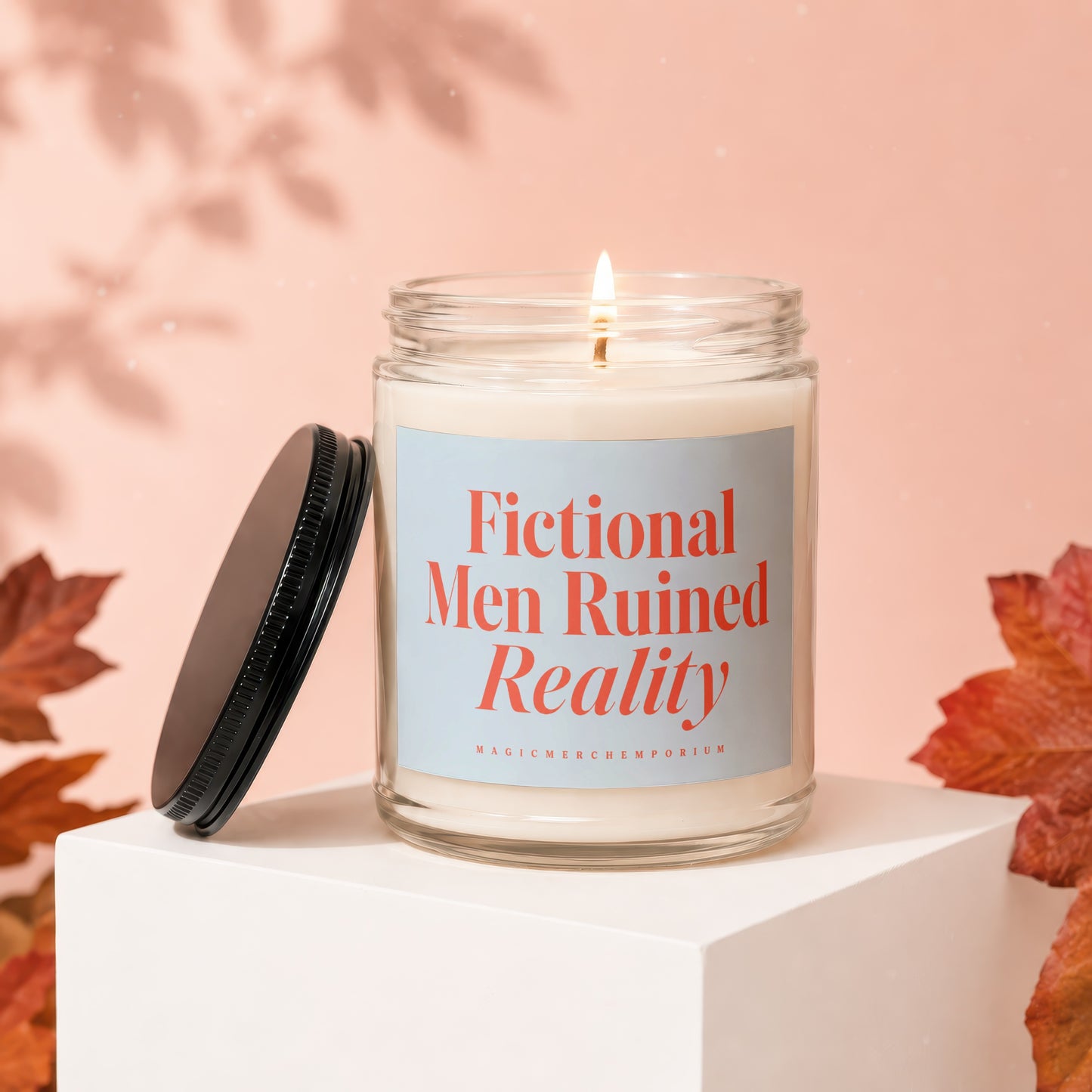Glass candle with lit wick labeled "Fictional Men Ruined Reality" and "MAGICMERCHTEPORIUM."