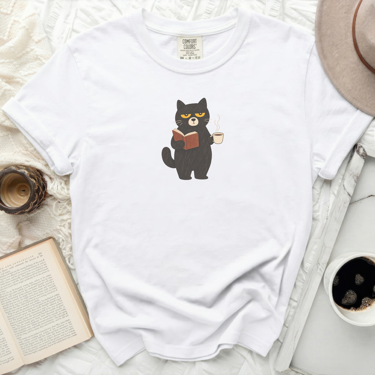 White Comfort Colors t-shirt with a black cat reading a book and holding coffee.