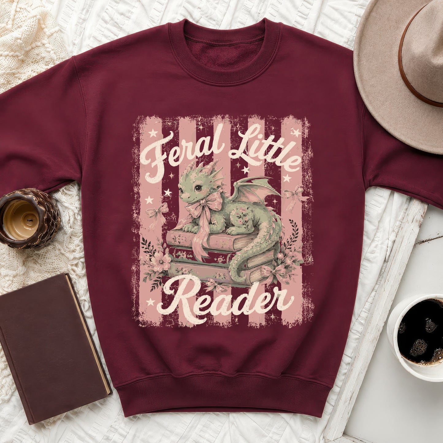 Maroon sweatshirt with dragon reading books graphic and text "Feral Little Reader."