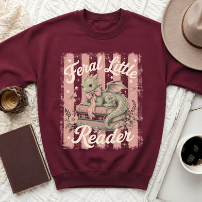 Maroon sweatshirt with dragon reading books graphic and text "Feral Little Reader."