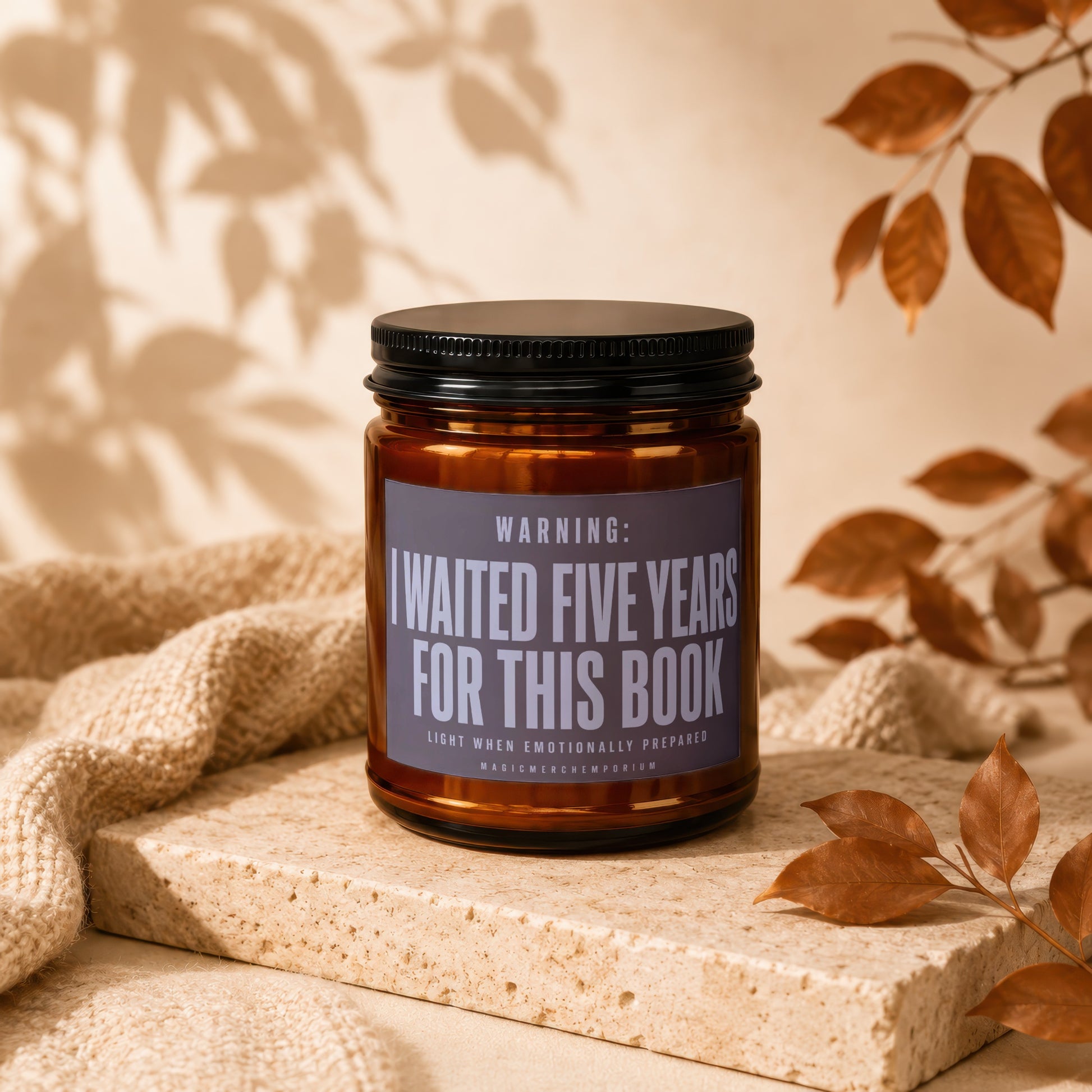 Candle with text "I waited five years for this book" on dark label.