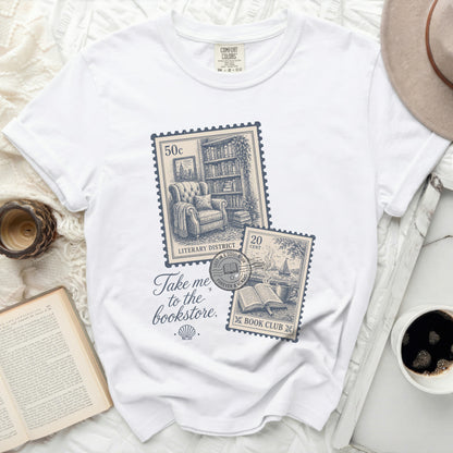 White t-shirt with postage stamps and "Take me to the bookstore" text.
