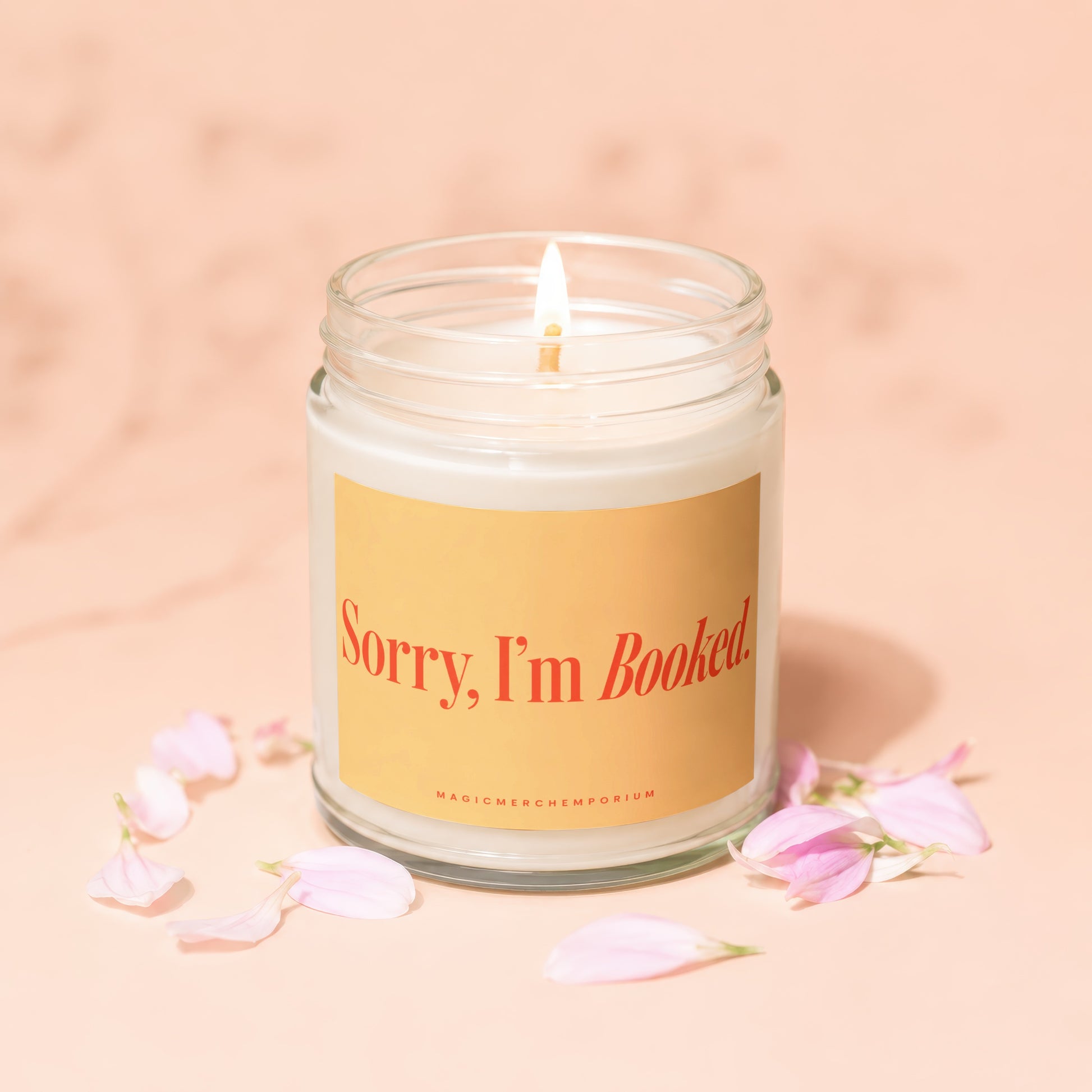 Glass jar candle with lit wick and text "Sorry, I'm Booked" surrounded by petals.