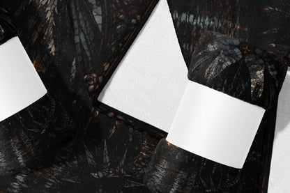 Dark patterned blanket with white paper band, folded on white surface.
