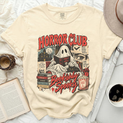 Cream t-shirt with "Horror Club" graphic featuring a ghost reading, black cat, and books.