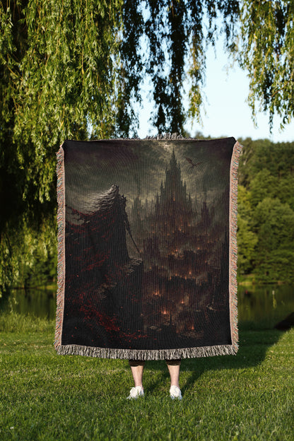 A person is standing in a grassy area, holding a large square blanket that features a dark, fantastical scene of a castle or cityscape.