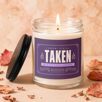 Burning candle with purple label reading "TAKEN BY A FICTIONAL DRAGON".