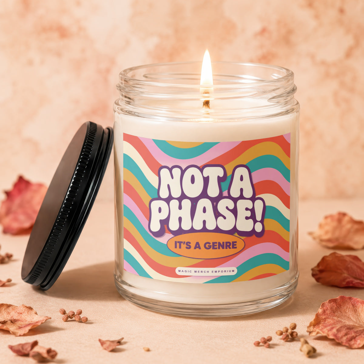 Lit candle in a glass jar with a label saying "NOT A PHASE! IT'S A GENRE".