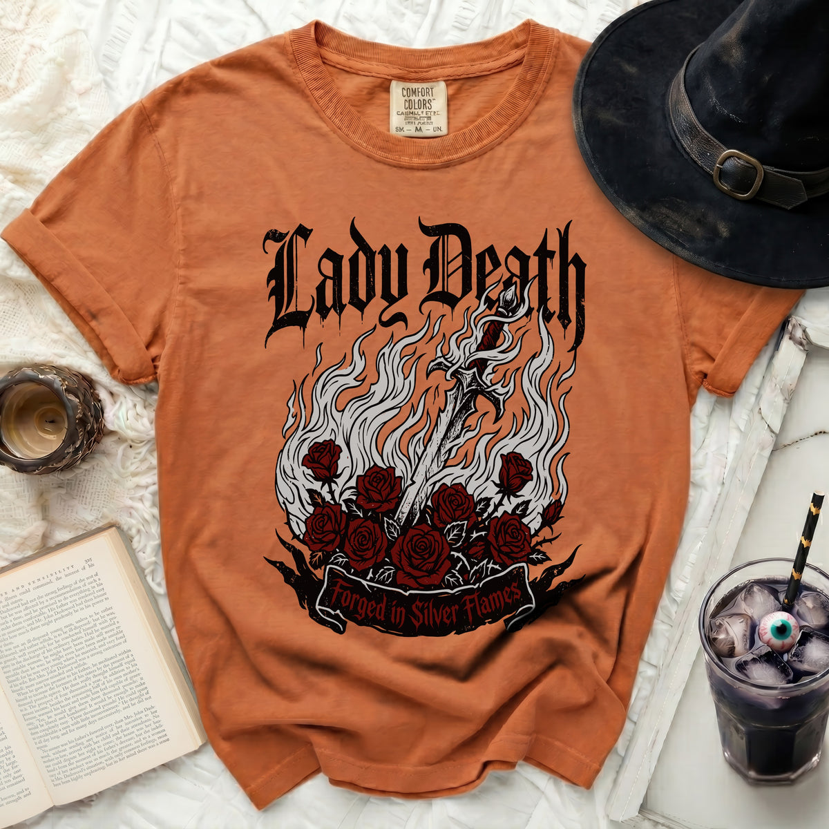 Orange t-shirt with Lady Death graphic, sword, roses, and "Forged in Silver Flames" text.