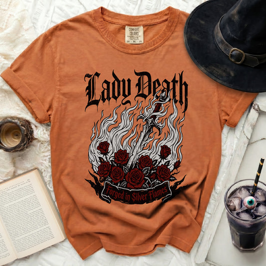 Orange t-shirt with Lady Death graphic, sword, roses, and "Forged in Silver Flames" text.