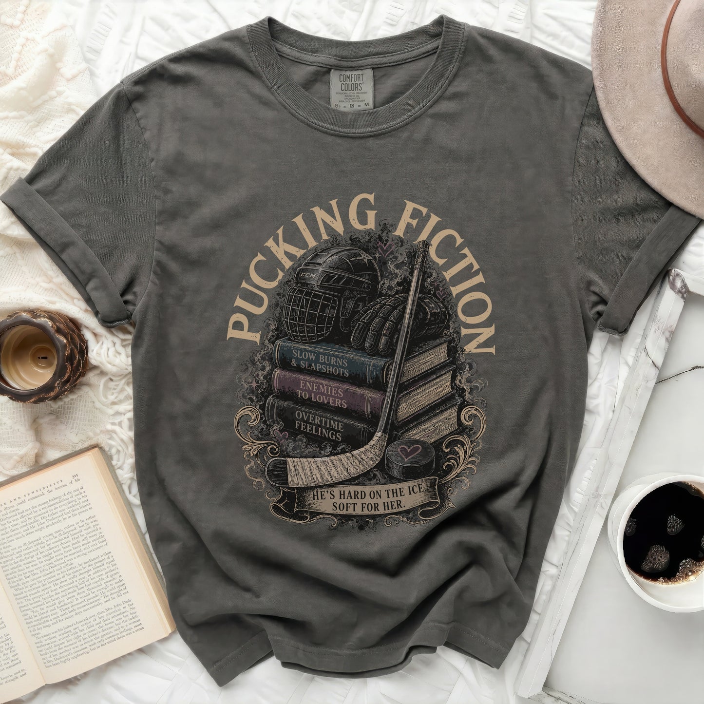 Dark gray t-shirt with stacked books, hockey gear, and "Pucking Fiction" text.